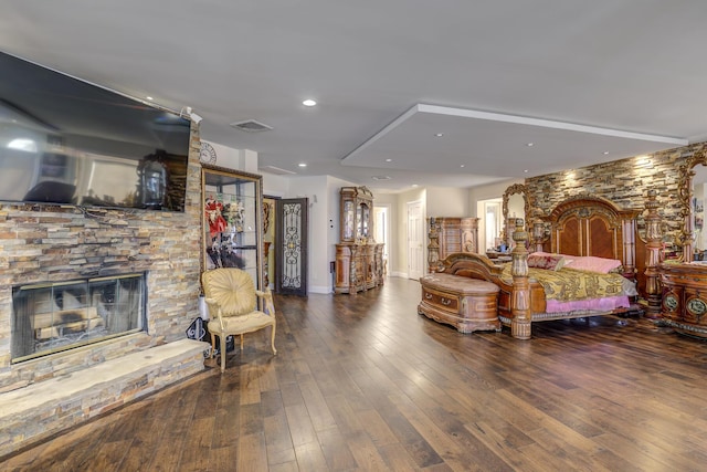 bedroom featuring recessed lighting, visible vents, wood finished floors, and a stone fireplace