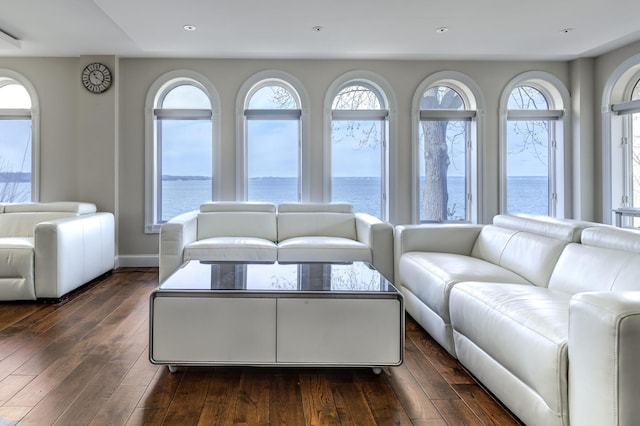 living room featuring a water view, baseboards, dark wood-style flooring, and recessed lighting