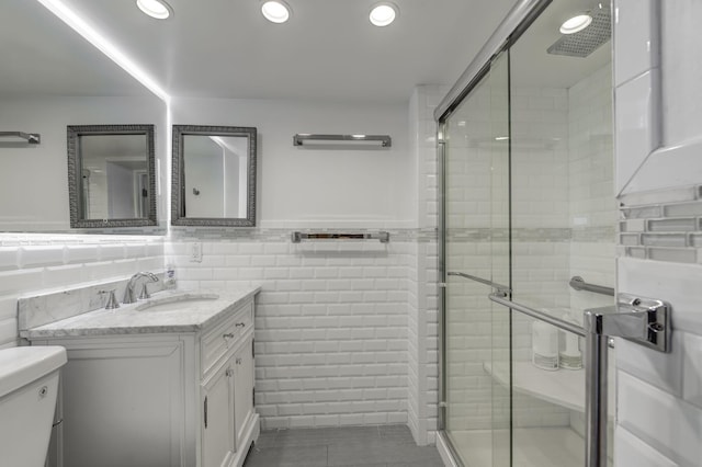 full bath with tile walls, recessed lighting, wainscoting, a shower stall, and vanity