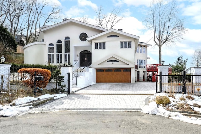 view of front facade featuring decorative driveway, fence, an attached garage, and stucco siding