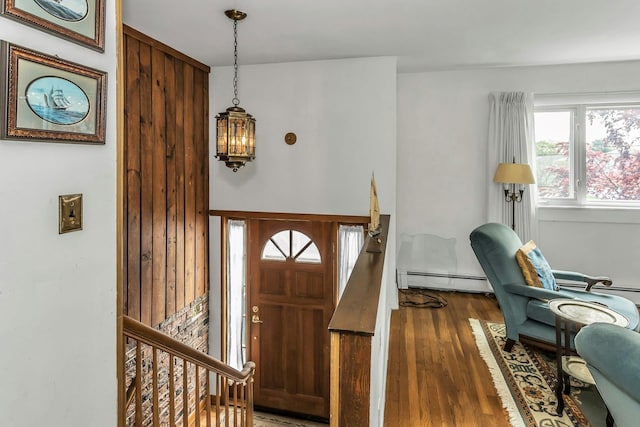 foyer entrance with baseboard heating and wood finished floors