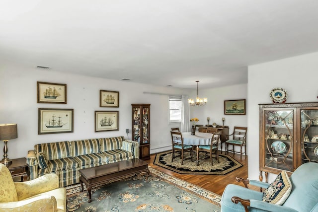 living area featuring visible vents, a baseboard heating unit, wood finished floors, and a notable chandelier