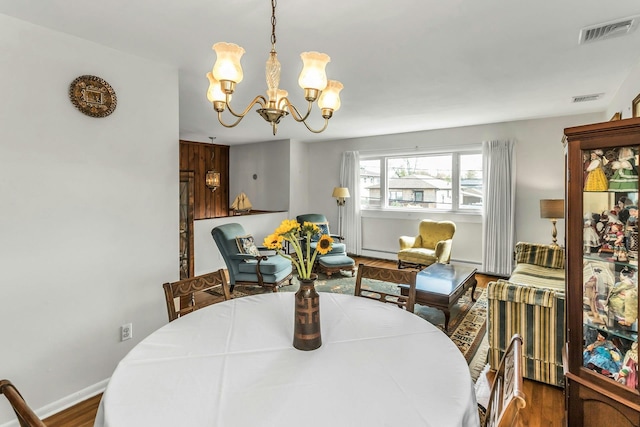 dining space featuring an inviting chandelier, wood finished floors, visible vents, and a baseboard radiator