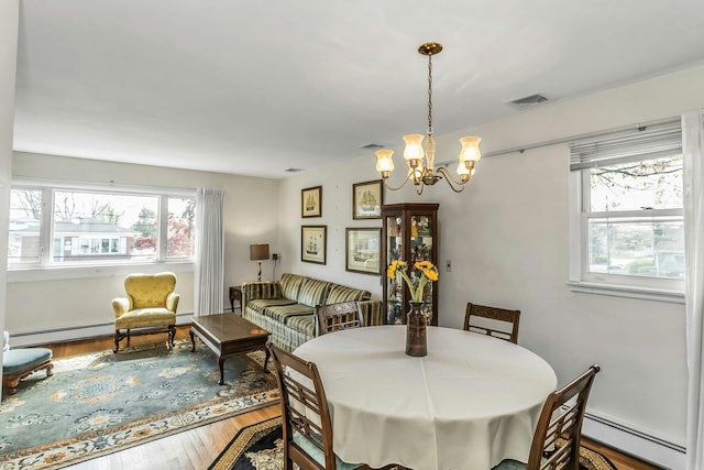 dining area with a baseboard radiator, a chandelier, wood finished floors, and visible vents