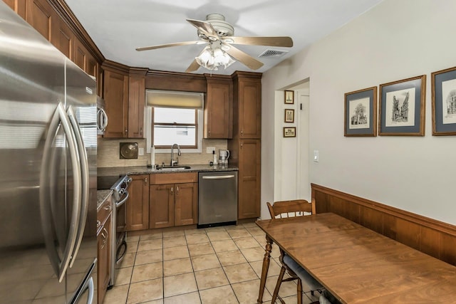 kitchen featuring appliances with stainless steel finishes, a sink, a ceiling fan, decorative backsplash, and visible vents