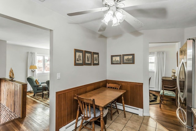 dining room with a baseboard radiator, wainscoting, ceiling fan, and a wealth of natural light