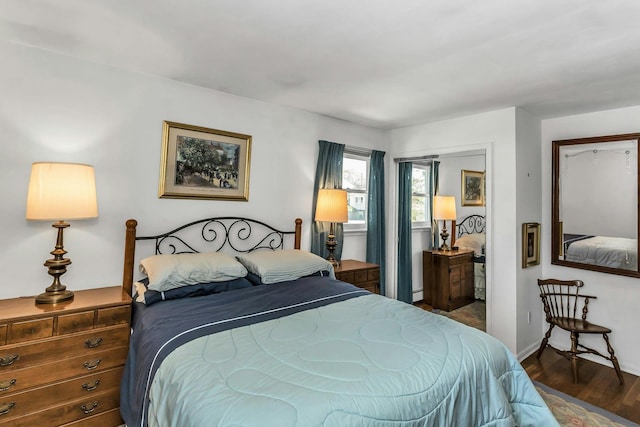 bedroom featuring baseboards, wood finished floors, baseboard heating, and a closet