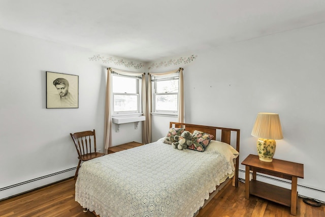 bedroom featuring a baseboard heating unit and dark wood finished floors