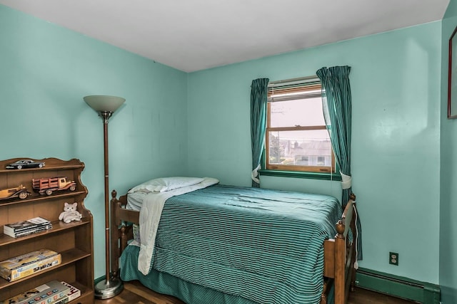 bedroom with baseboard heating and wood finished floors