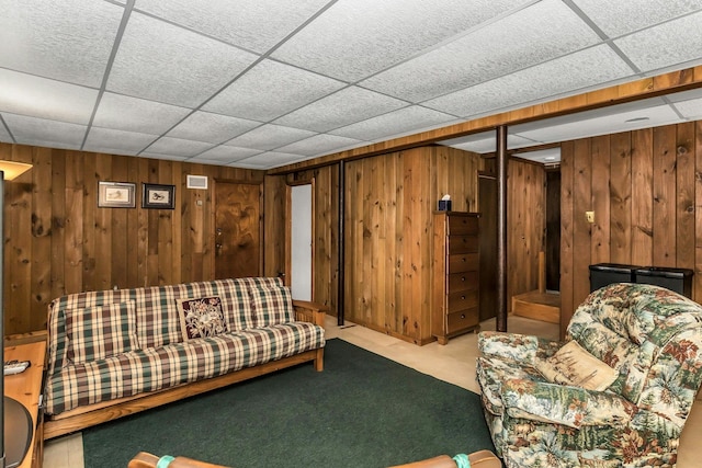 carpeted living area featuring visible vents, wood walls, and a paneled ceiling