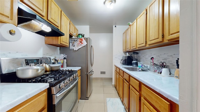 kitchen with stainless steel gas range oven, light tile patterned flooring, under cabinet range hood, visible vents, and tasteful backsplash