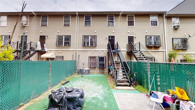 rear view of property featuring cooling unit, a fenced backyard, and stairs