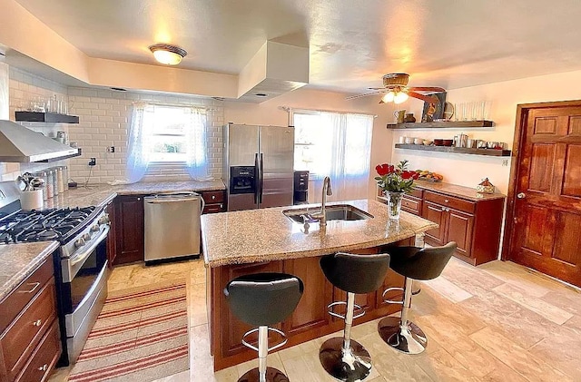 kitchen with a breakfast bar area, tasteful backsplash, appliances with stainless steel finishes, a sink, and light stone countertops