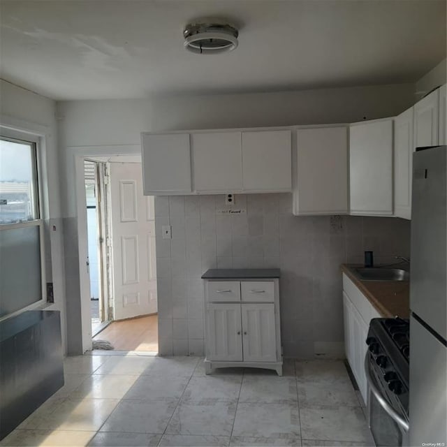 kitchen featuring dark countertops, white cabinets, stainless steel appliances, and a sink