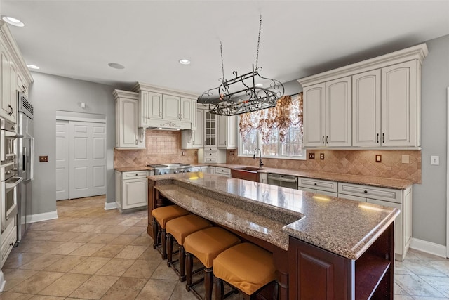 kitchen featuring a sink, a kitchen island, appliances with stainless steel finishes, backsplash, and glass insert cabinets