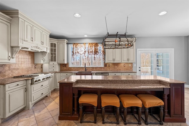 kitchen featuring appliances with stainless steel finishes, glass insert cabinets, a sink, and a center island