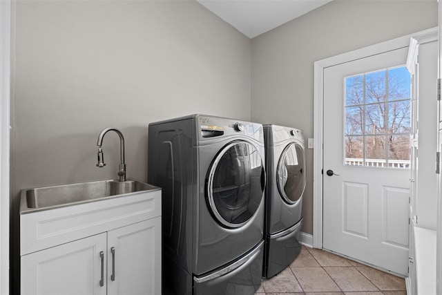 clothes washing area with a sink, light tile patterned flooring, washing machine and clothes dryer, and cabinet space