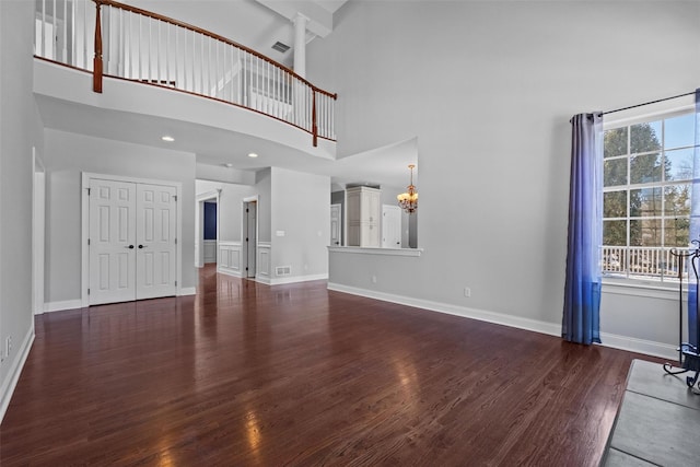 unfurnished living room with dark wood-style flooring, recessed lighting, visible vents, a towering ceiling, and baseboards