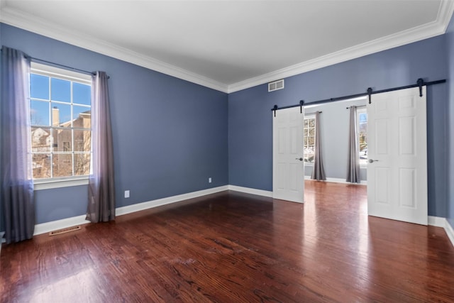 unfurnished room featuring ornamental molding, a barn door, dark wood finished floors, and visible vents