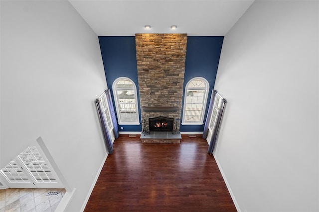 unfurnished living room featuring plenty of natural light, dark wood finished floors, a fireplace, and baseboards