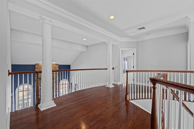 corridor with wood finished floors, an upstairs landing, visible vents, ornamental molding, and decorative columns