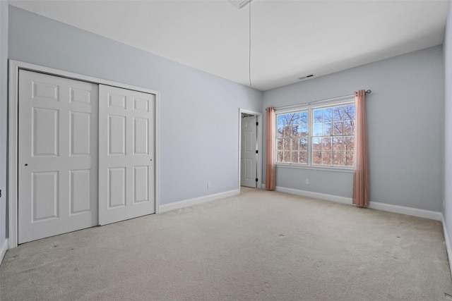 unfurnished bedroom featuring baseboards, visible vents, a closet, and light colored carpet