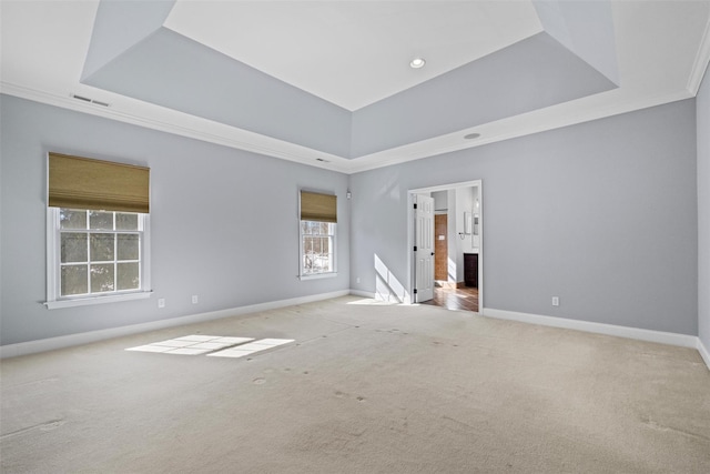 empty room with a raised ceiling, light colored carpet, and baseboards