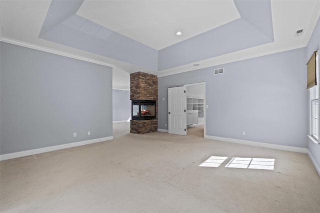 unfurnished living room featuring a fireplace, a raised ceiling, visible vents, light carpet, and baseboards