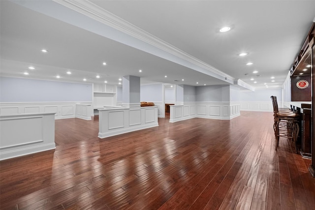 unfurnished living room featuring a decorative wall, recessed lighting, ornamental molding, wainscoting, and dark wood finished floors