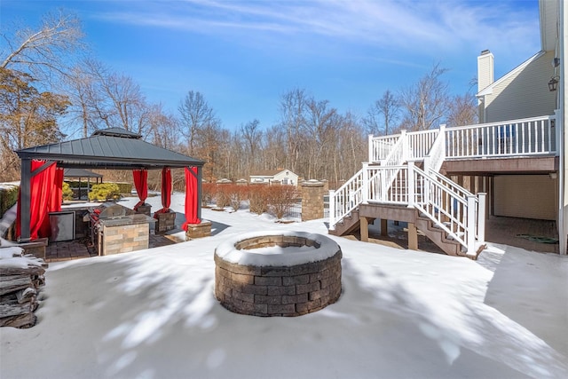 snow covered patio featuring a wooden deck, a fire pit, a gazebo, and stairs