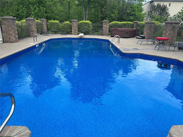 view of pool with a patio area, a hot tub, fence, and a fenced in pool