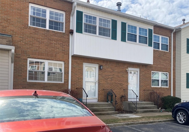 view of property with uncovered parking and brick siding