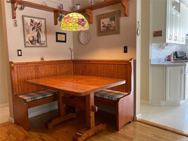 dining area with breakfast area, light wood-type flooring, and a wainscoted wall