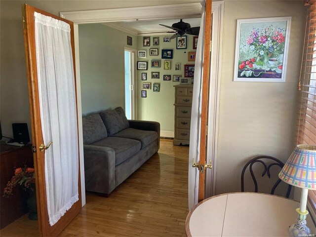 living room featuring crown molding, ceiling fan, and light wood-style flooring