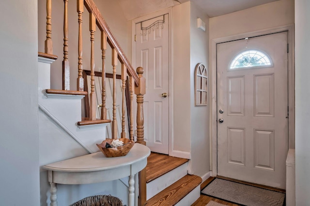 foyer entrance featuring baseboards, wood finished floors, and stairway