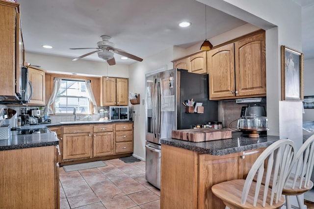 kitchen with a peninsula, ceiling fan, appliances with stainless steel finishes, and tasteful backsplash