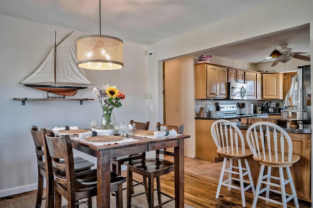 dining space with light wood-style flooring and ceiling fan with notable chandelier