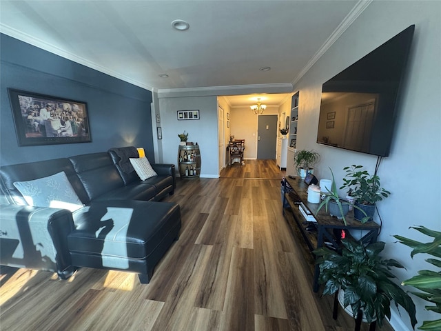 living room with ornamental molding, a notable chandelier, baseboards, and wood finished floors