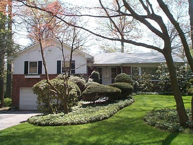 view of front of home with a garage, driveway, brick siding, and a front yard