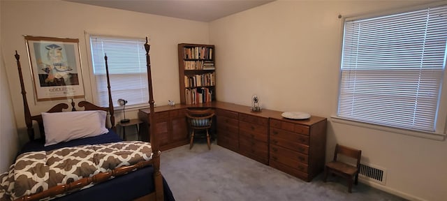 carpeted bedroom featuring visible vents and built in desk