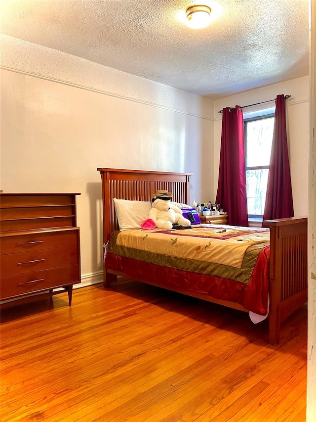 bedroom with a textured ceiling and light wood finished floors