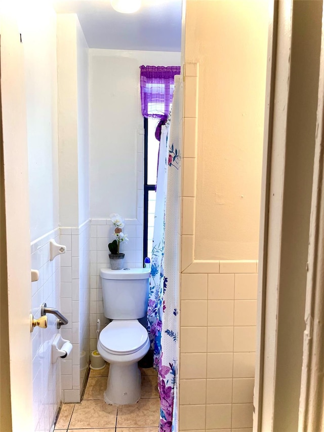 bathroom with wainscoting, tile patterned flooring, toilet, and tile walls