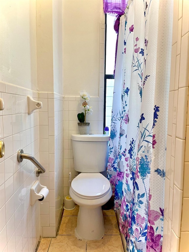 full bathroom with a stall shower, tile walls, toilet, and tile patterned floors