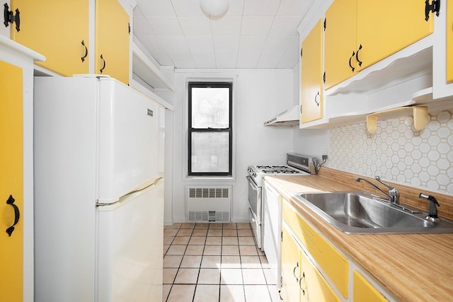 kitchen featuring freestanding refrigerator, light countertops, under cabinet range hood, double oven range, and a sink