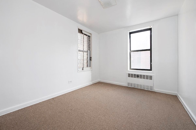 empty room featuring radiator, carpet flooring, and baseboards