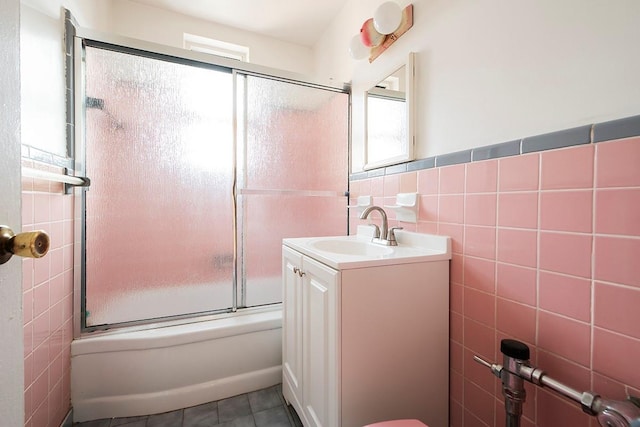 full bath featuring shower / bath combination with glass door, vanity, tile walls, wainscoting, and tile patterned floors