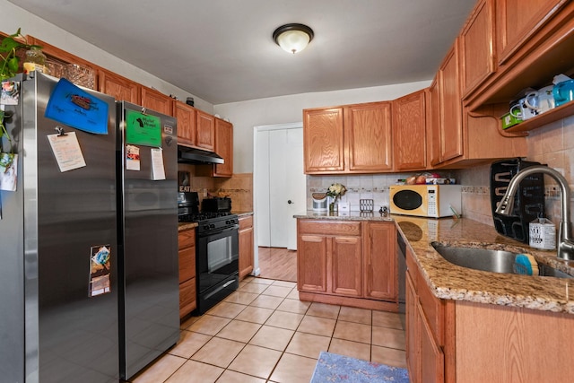 kitchen featuring light tile patterned floors, stainless steel appliances, tasteful backsplash, a sink, and under cabinet range hood