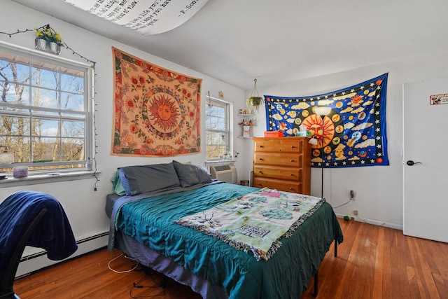 bedroom with baseboard heating, cooling unit, and hardwood / wood-style flooring