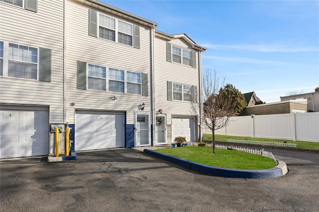 multi unit property featuring a garage, driveway, and fence