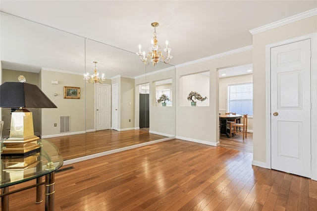 interior space with a chandelier, baseboards, visible vents, and hardwood / wood-style floors